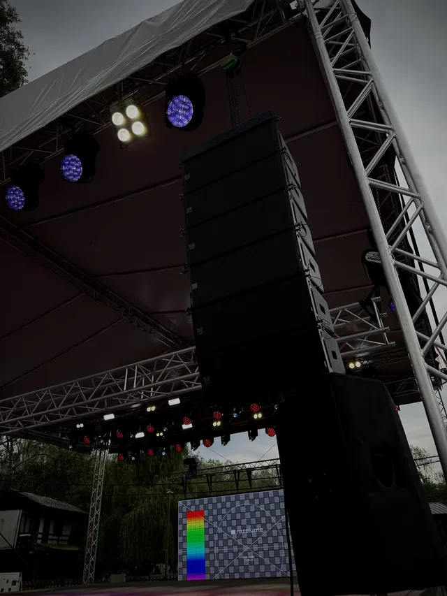 Függesztett line array hangrendszer fedett színpadon, háttérben LED fal